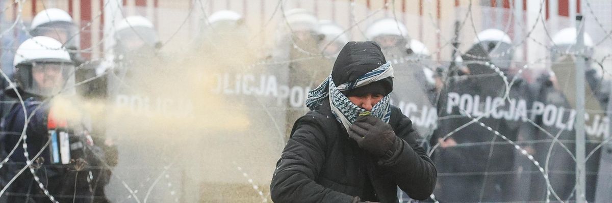 Polish riot police officers and a migrant are seen near the Bruzgi-Kuznica crossing point on the Belarusian-Polish border.