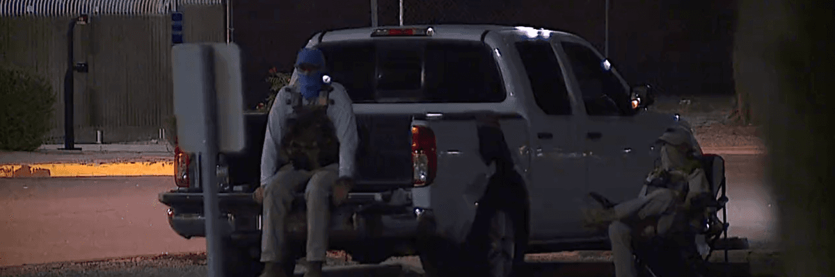 Poll watchers dressed in tactical gear watch a ballot dropbox location