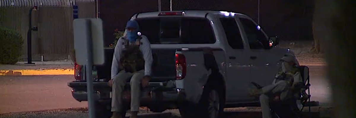 Poll watchers dressed in tactical gear watch a ballot dropbox location