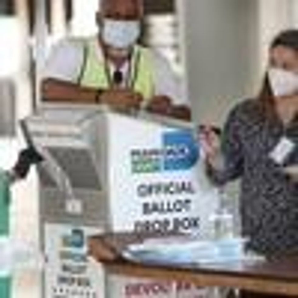 Poll workers help a voter put their mail-in ballot in an official Miami-Dade County ballot drop box on August 11, 2020 in Florida. (Photo: Joe Raedle/Getty Images)
