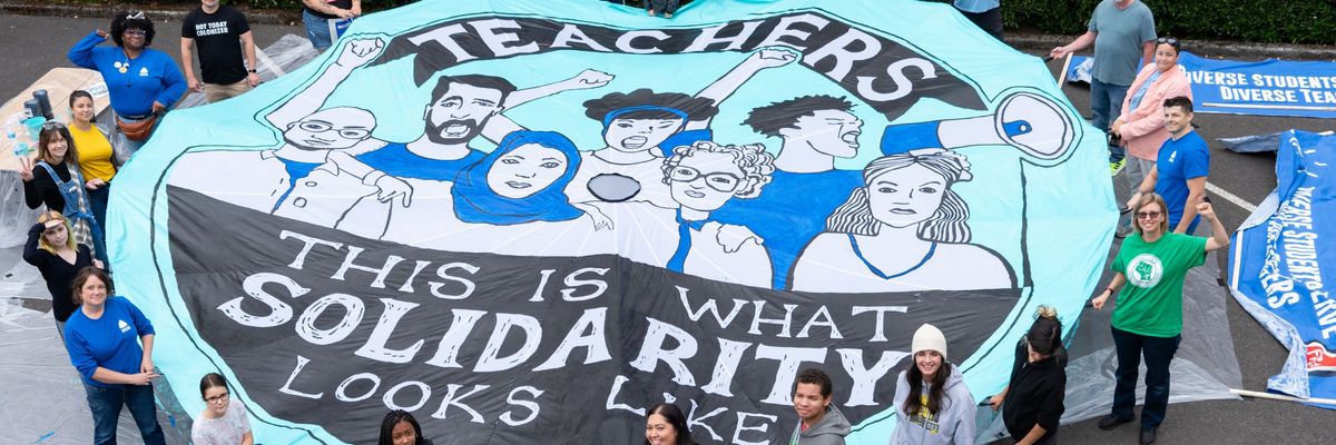 Portland teachers and supporters unfurl a banner rading "this is what solidarity looks like."