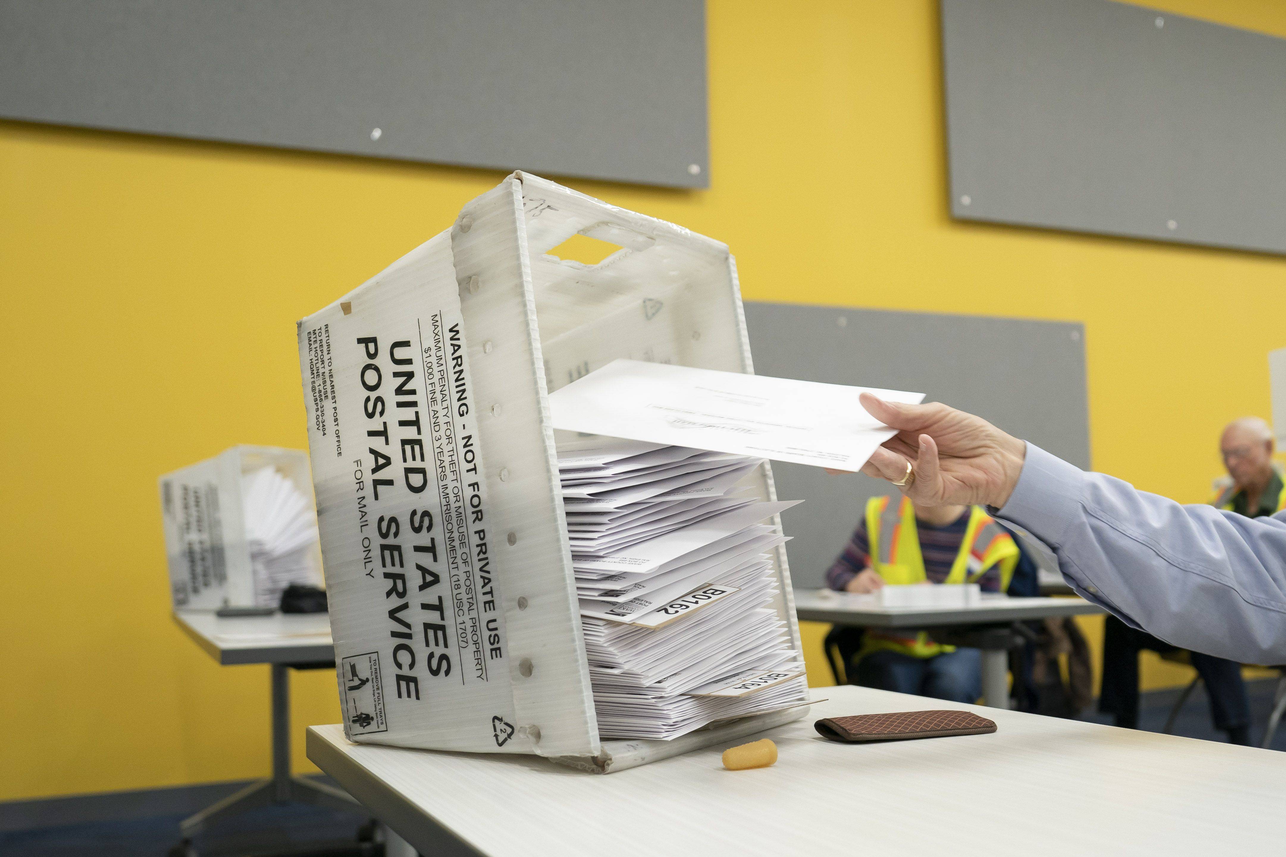 postal workers sort mailed ballots