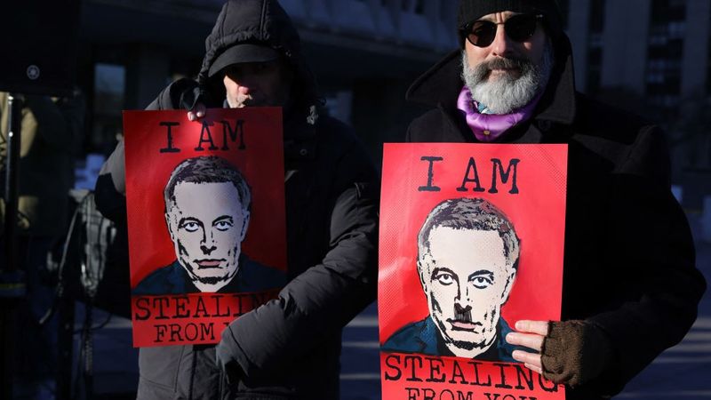Posters of Elon Musk that say "I am stealing from you."
