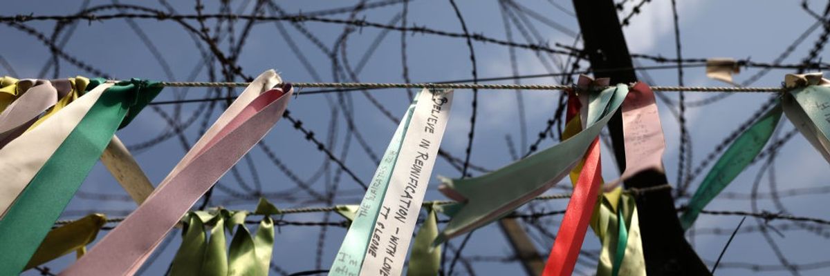 Prayer ribbons hang from a barbed-wire fence.