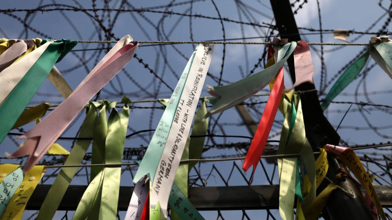 Prayer ribbons hang from a barbed-wire fence.