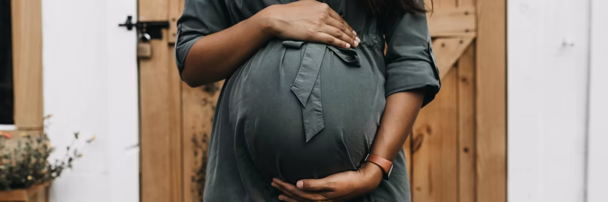 Pregnant person holds belly.