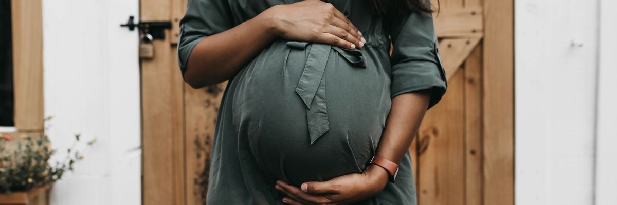 Pregnant person holds belly.
