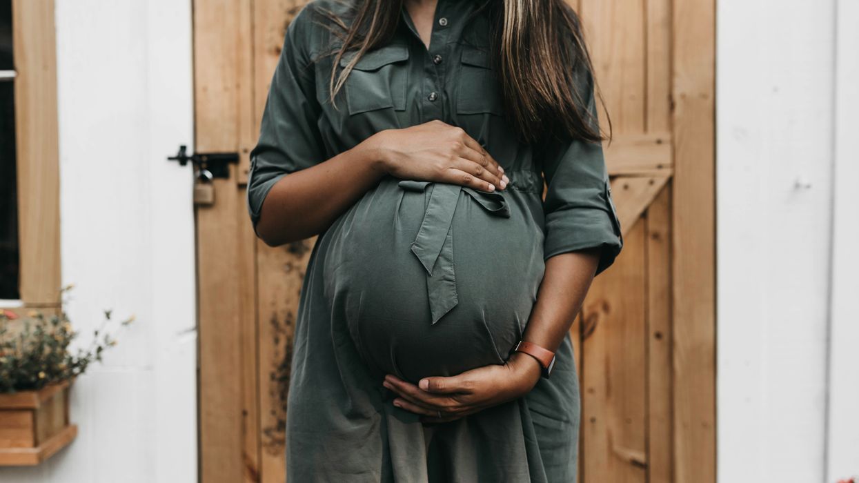 Pregnant person holds belly.