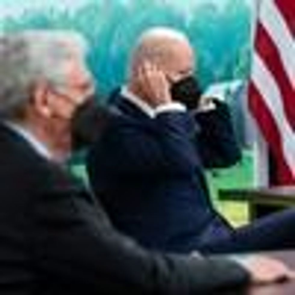 President Joe Biden removes his mask during a meeting