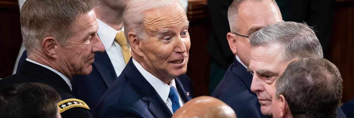 President Joe Biden smiles while addressing a stone-faced General Mark Milley.