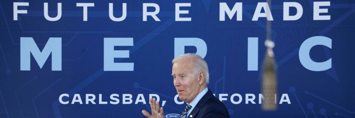 President Joe Biden speaks in front of a blue banner.