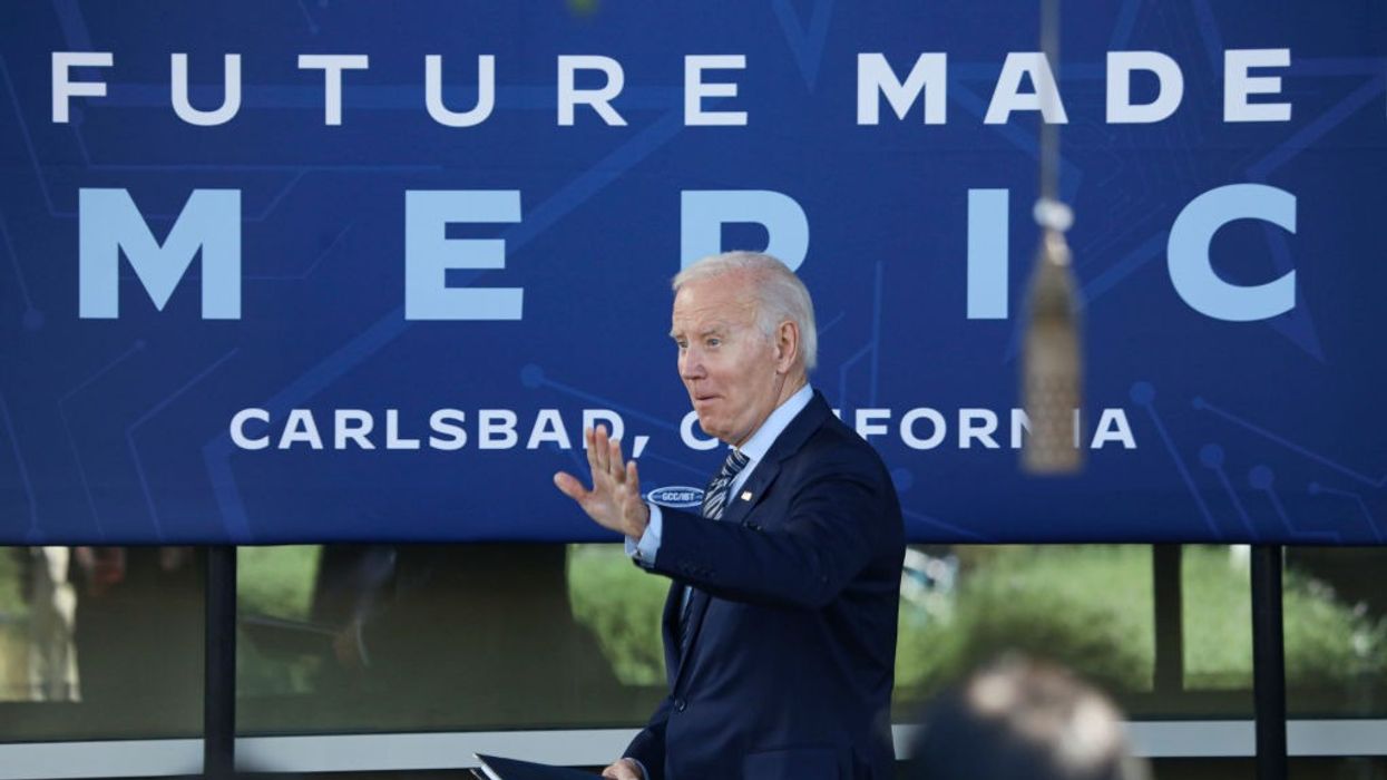 President Joe Biden speaks in front of a blue banner.