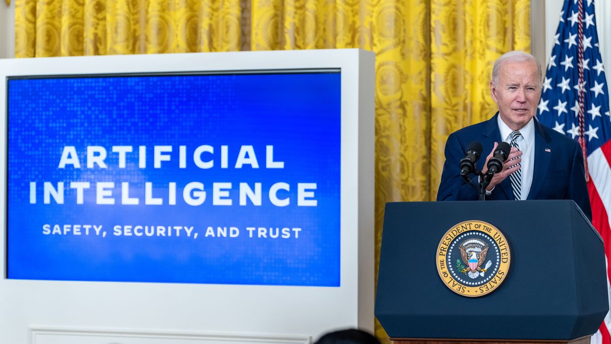 President Joe Biden speaks near a screen reading "Artificial Intelligence: Safety, Security, and Trust"