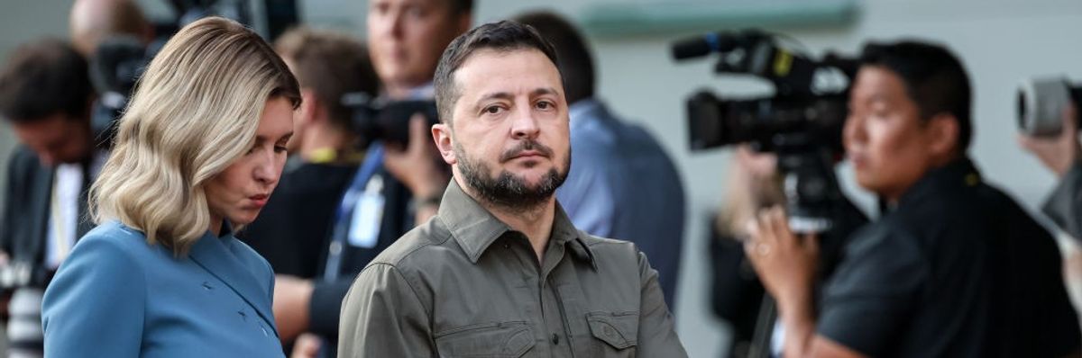 President of Ukraine Volodymyr Zelenskyy (R) and Olena Zelenska (L) walk past journalists holding hands.