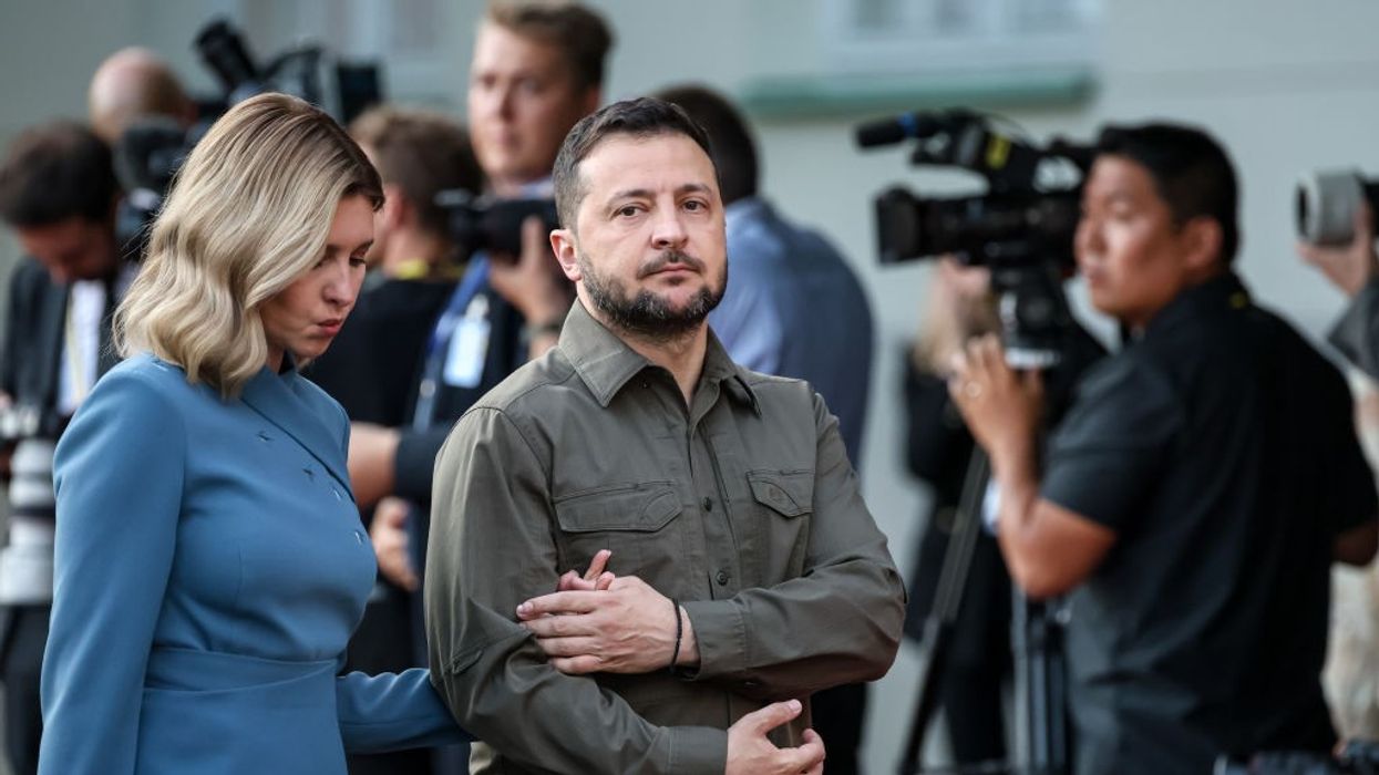 President of Ukraine Volodymyr Zelenskyy (R) and Olena Zelenska (L) walk past journalists holding hands.