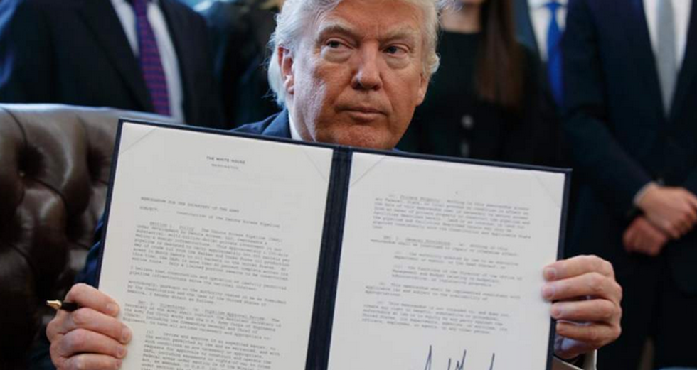 President Trump showed off his signature on an executive order designed to advance construction on the Dakota Access pipeline during an Oval Office signing ceremony last year. Friday's signing of a controversial law that reauthorizes warrantless surveillance happened without cameras.  (Photo: Evan Vucci/AP)