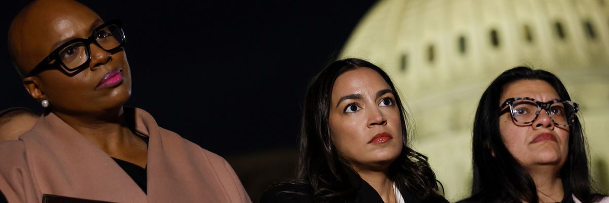 Pressley, Ocasio-Cortez, and Tlaib listen outside U.S. Capitol building at night.