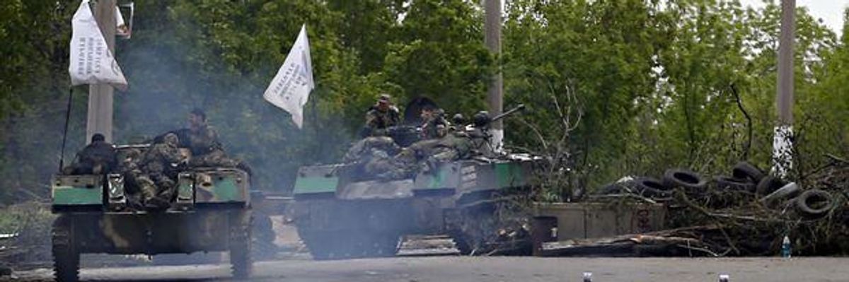 Pro-Russia gunmen on armored personal carriers passing by barricades on a road leading into Slavyansk