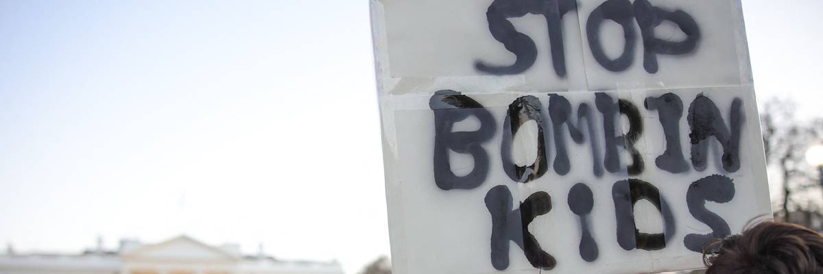 Protest sign in front of White House reads, "Stop bombing kids."