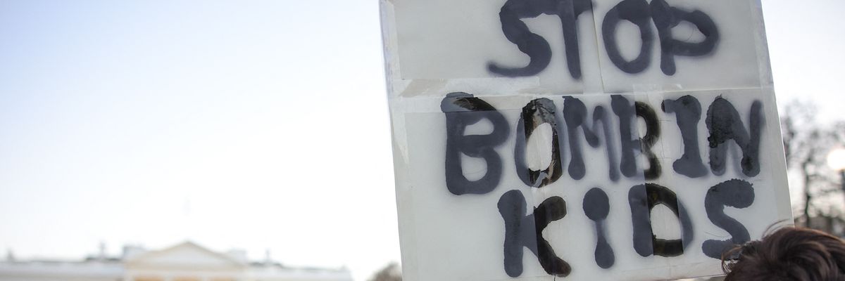 Protest sign in front of White House reads, "Stop bombing kids."