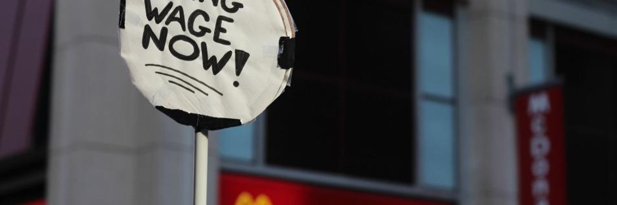 Protest sign reads: LIVING WAGE NOW!