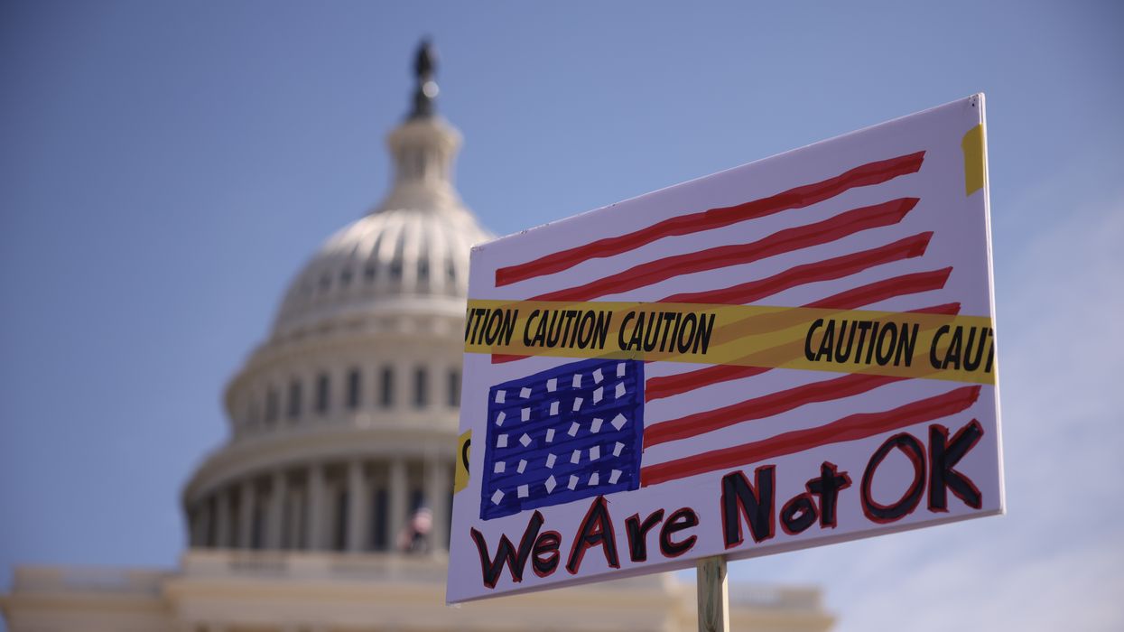 Protest sign with U.S. flag upside down covered with caution tape saying, "We are not OK."