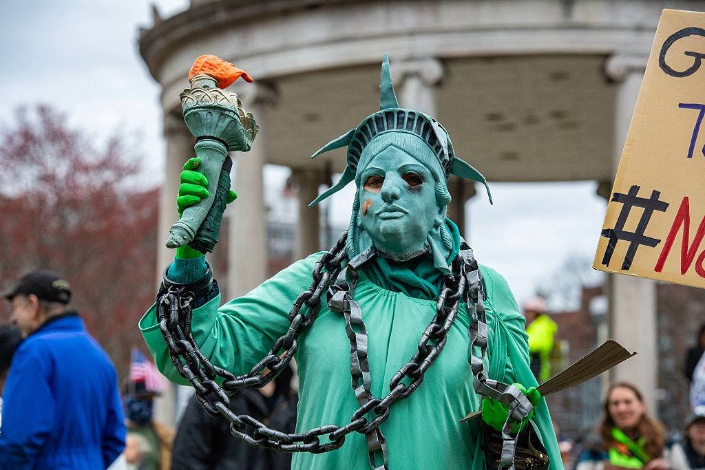 Protester dresses as Statue of Liberty in chains.