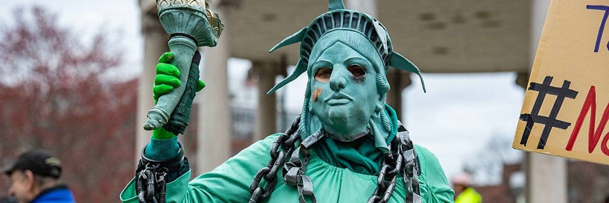 Protester dresses as Statue of Liberty in chains.