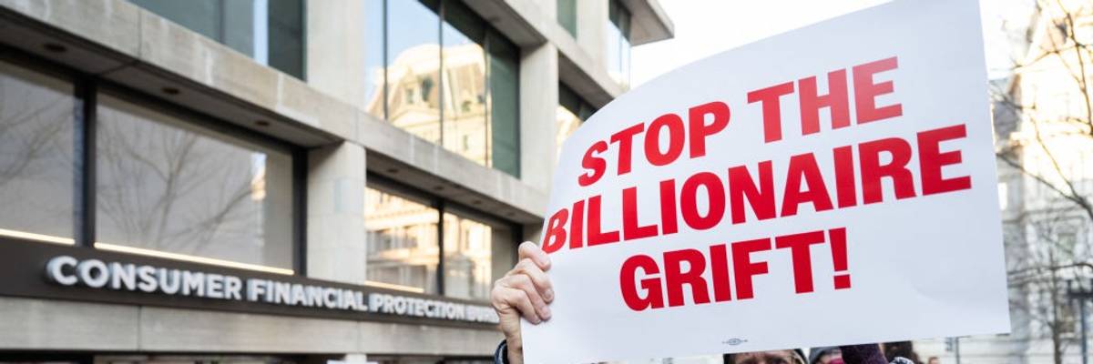 Protester holds sign reading, "Stop the billionaire grift" outside CFPB headquarters.