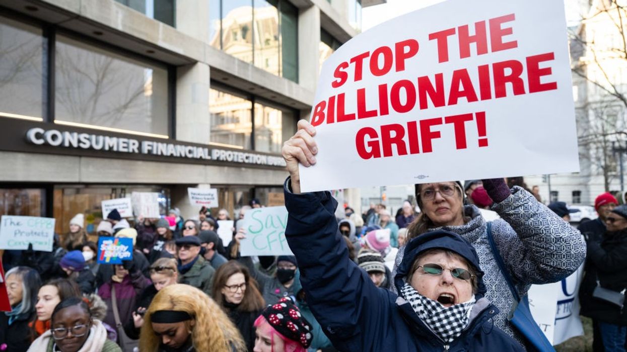 Protester holds sign reading, "Stop the billionaire grift" outside CFPB headquarters.