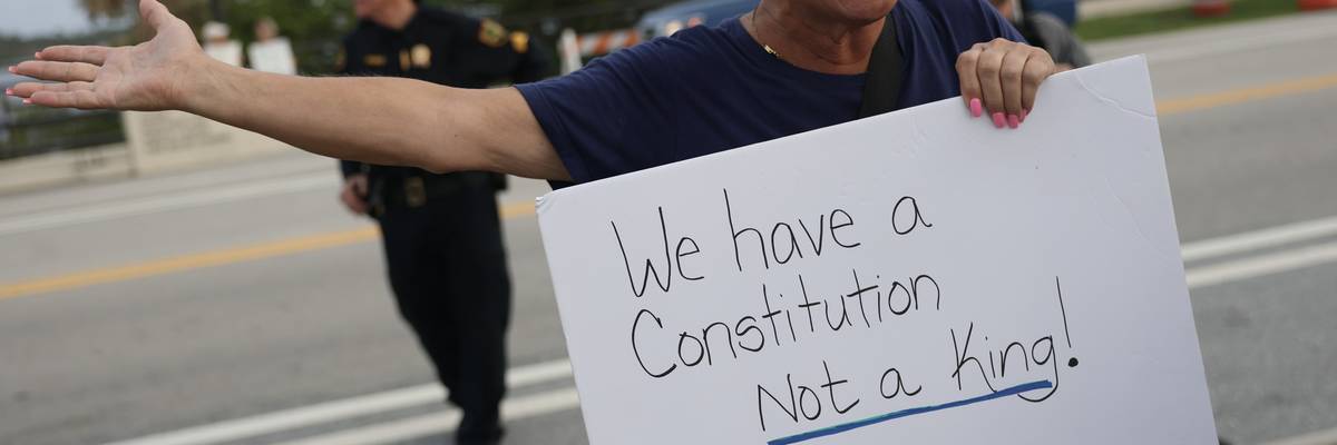 Protester holds sign reading, "We have a Constitution, not a king!"