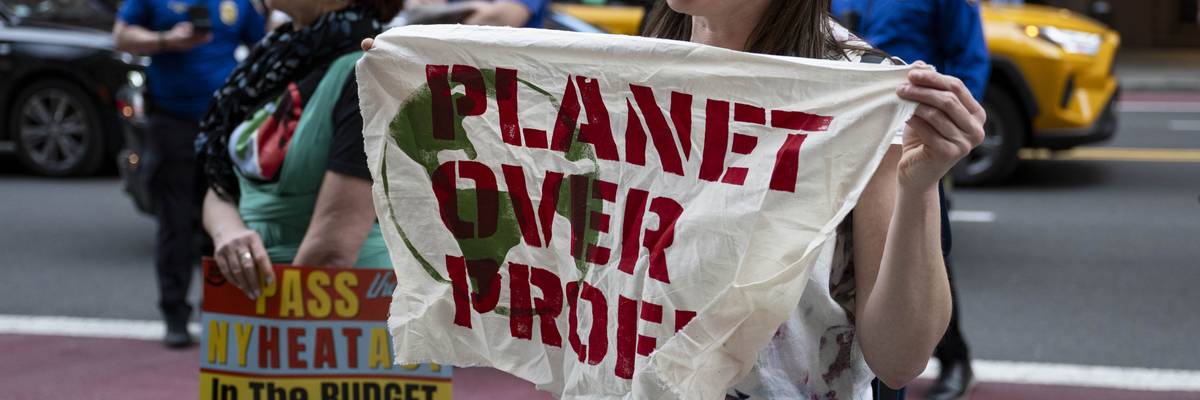 Protester holds sign saying, "Planet over profit."