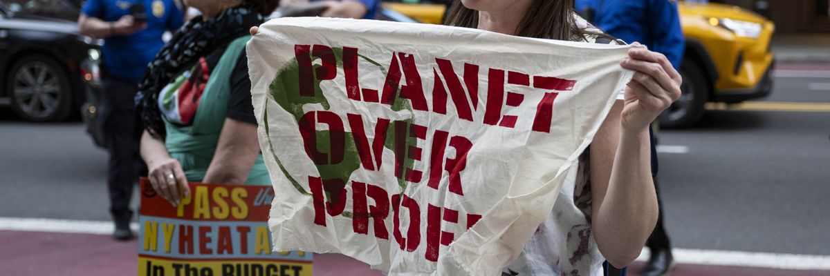 Protester holds sign saying, "Planet over profit."