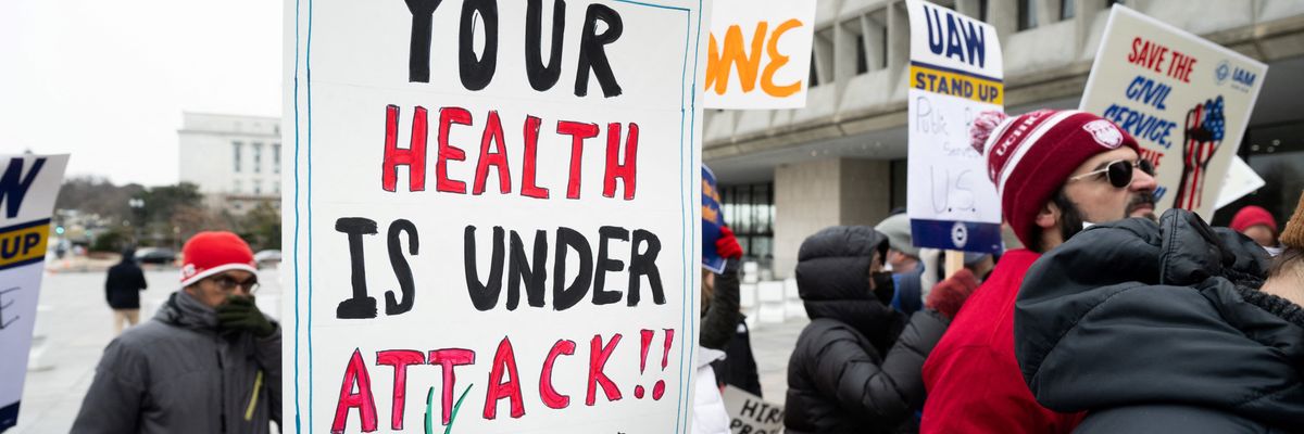 Protester holds sign saying, "Your health is under attack."