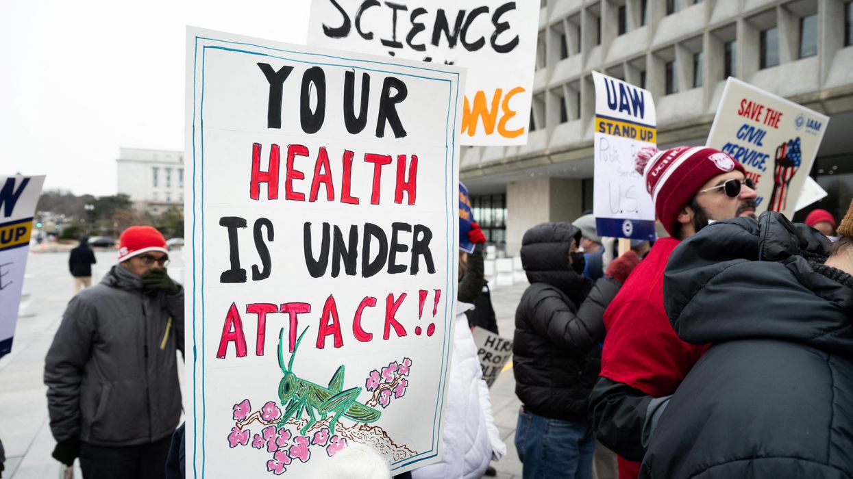 Protester holds sign saying, "Your health is under attack."