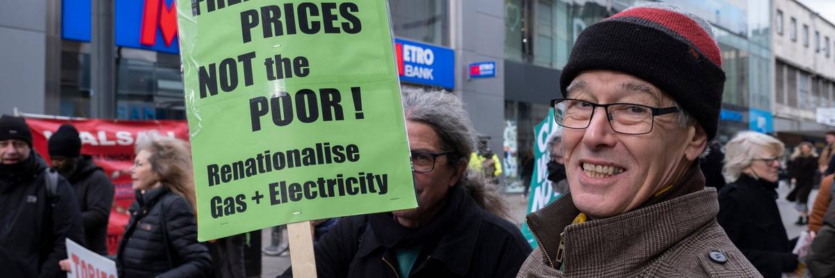 protester holds sign that says freeze prices not the poor