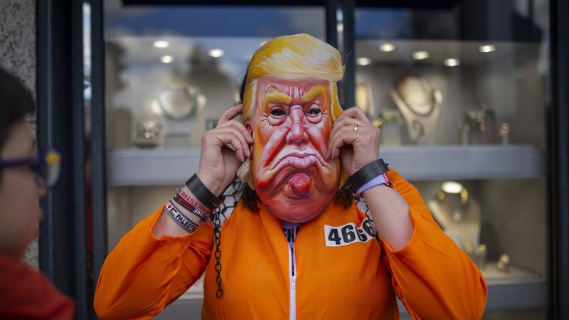 Protester in Trump mask and prison jumpsuit.