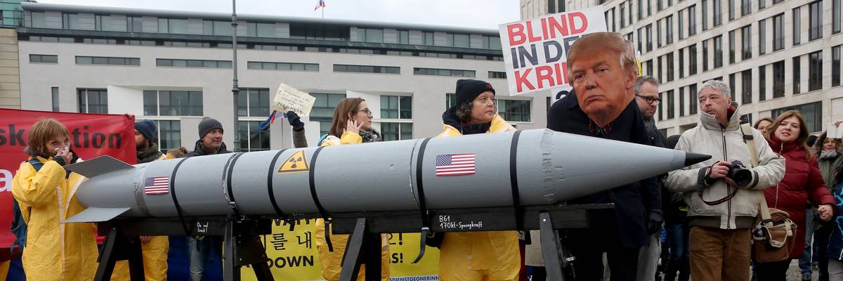 Protester wears mask of Trump and guides model nuclear rocket.