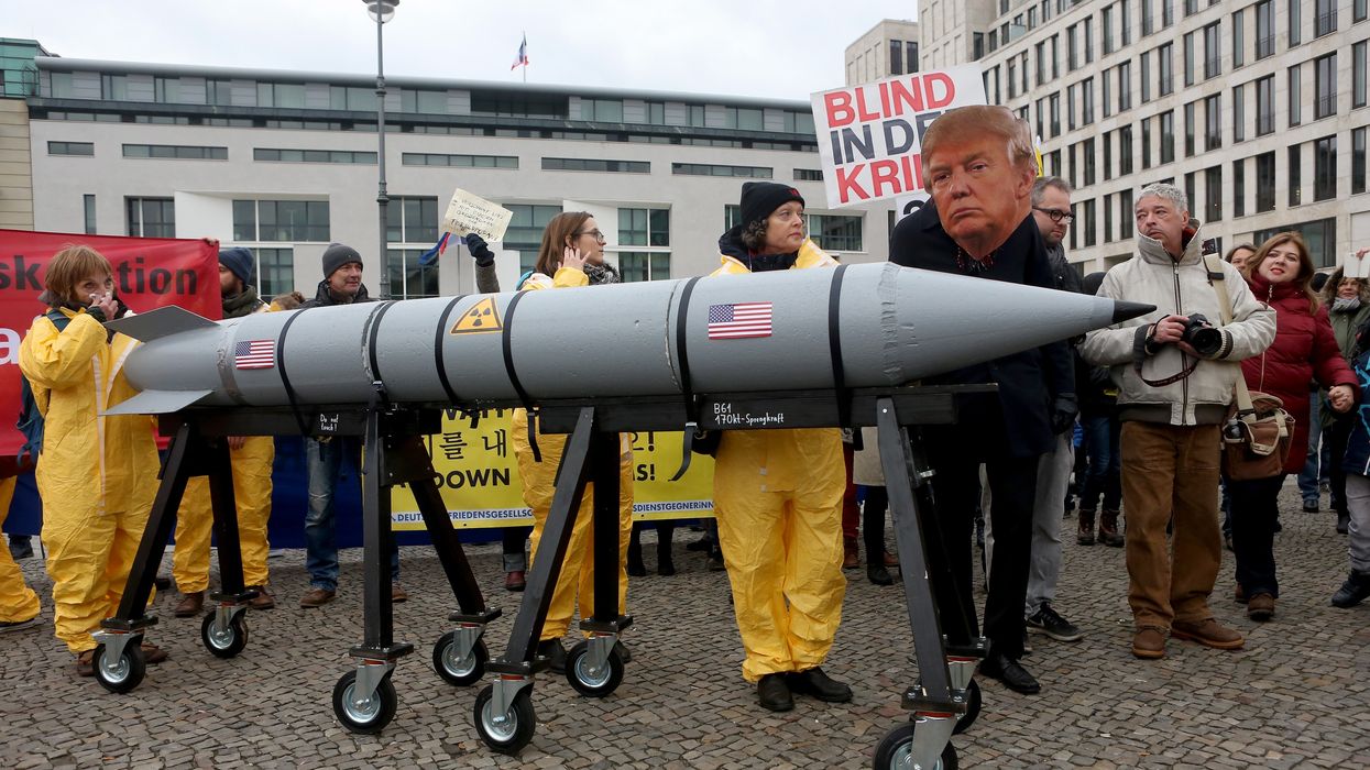 Protester wears mask of Trump and guides model nuclear rocket.