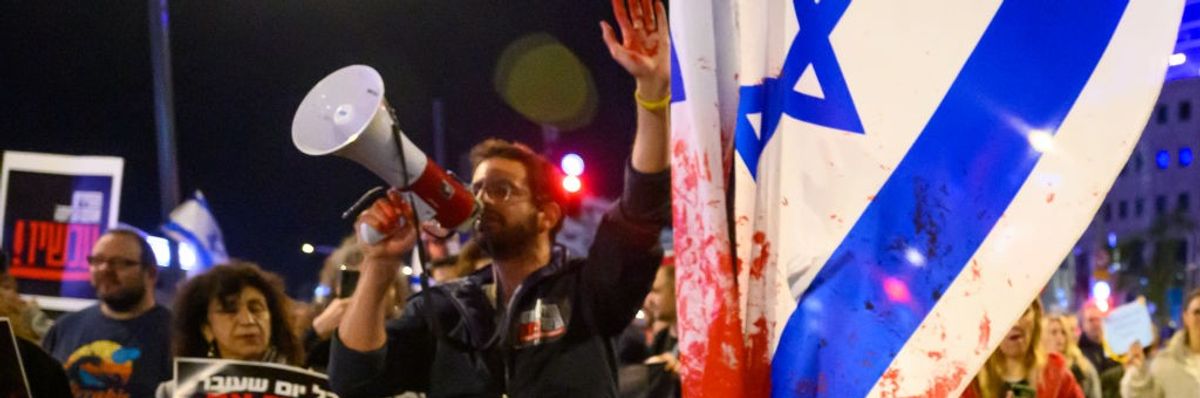 protester with red paint on his hand marches through the streets after demonstrating outside the Israel Defense Forces