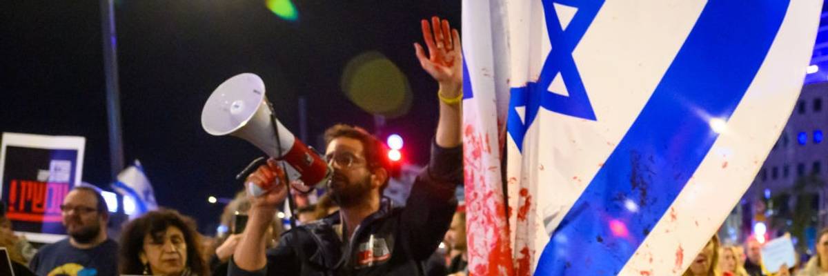 Protester with red paint on his hand marches through the streets.