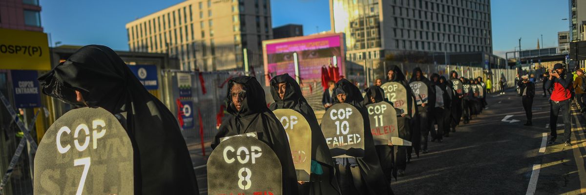 Protesters are seen carrying gravestones with the numbers of COP conferences claiming they have failed during a protest outside the entrance to the COP26 site