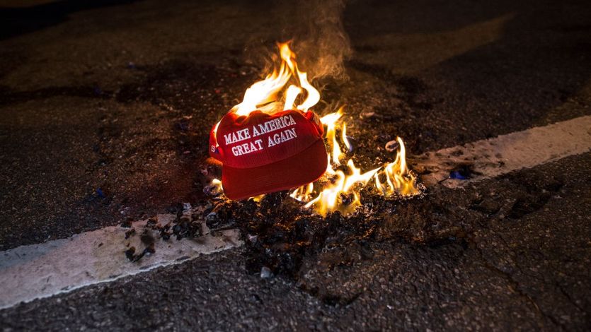 Protesters burn a "Make America Great Again" hat