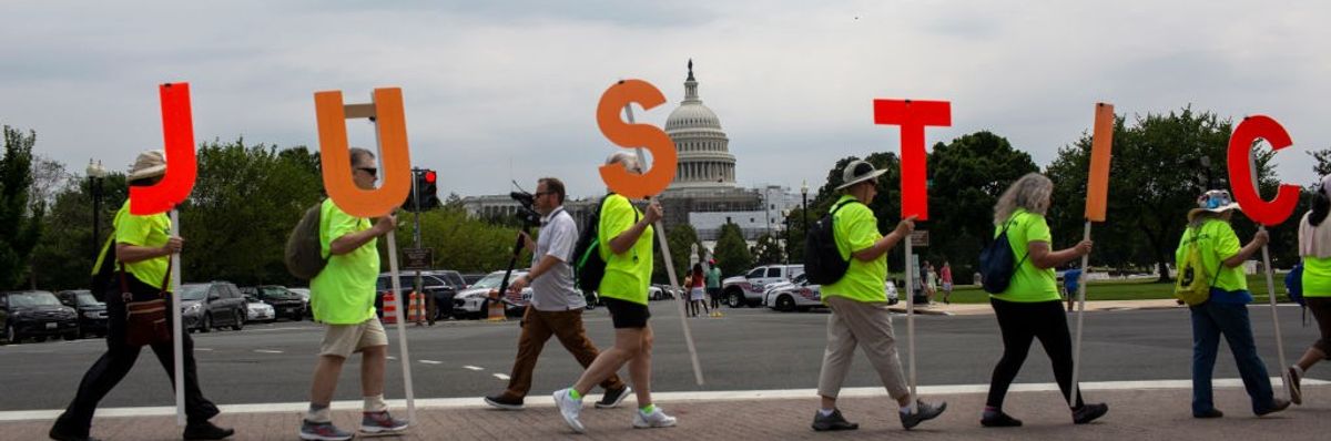 Protesters carrying orange letters spelling Justice. 