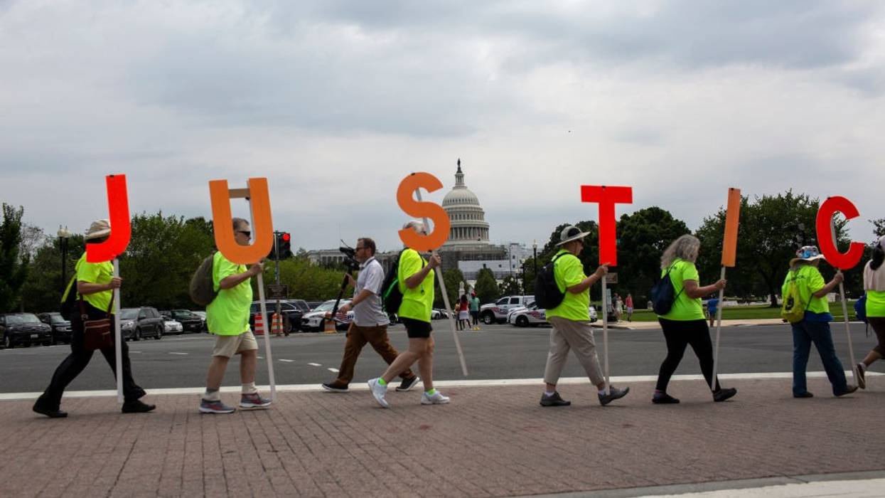 Protesters carrying orange letters spelling Justice.
