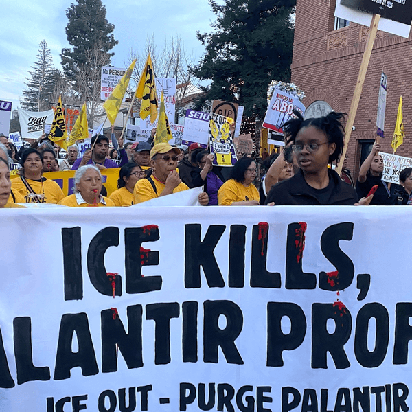 Protesters hold a banner reading "ICE Kills, Palantir Profits"