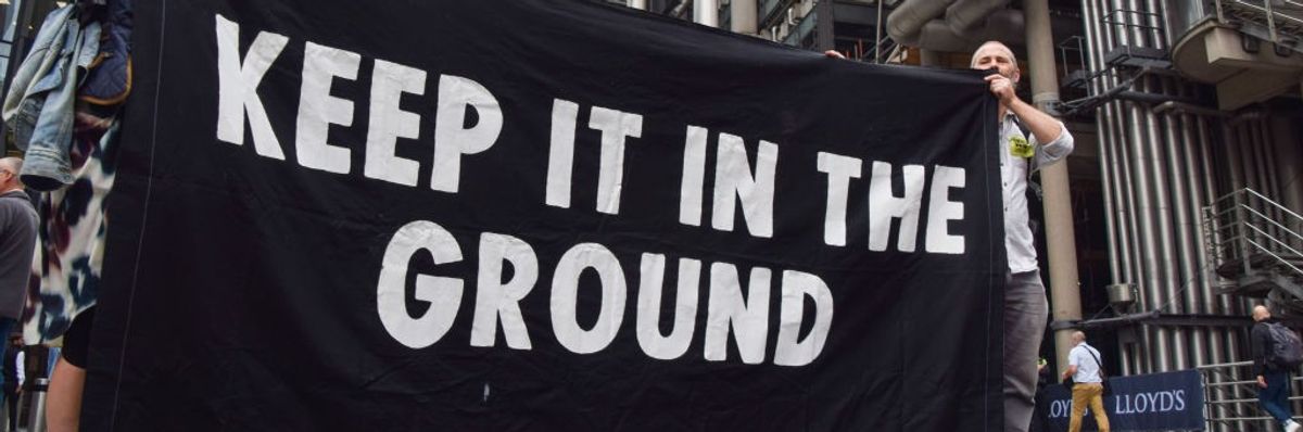 Protesters hold a black "Keep It In The Ground" banner with white letters.