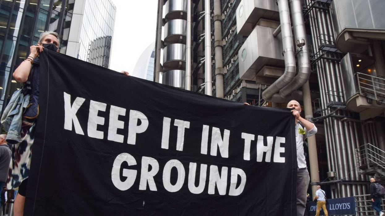 Protesters hold a black "Keep It In The Ground" banner with white letters.