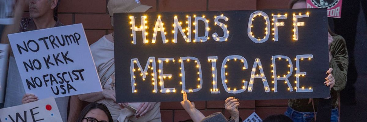 Protesters hold a sign reading, "Hands off Medicare."
