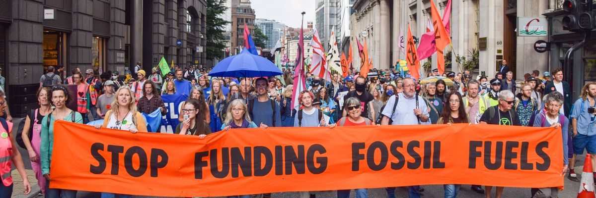 Protesters hold a "Stop Funding Fossil Fuels'' banner while marching